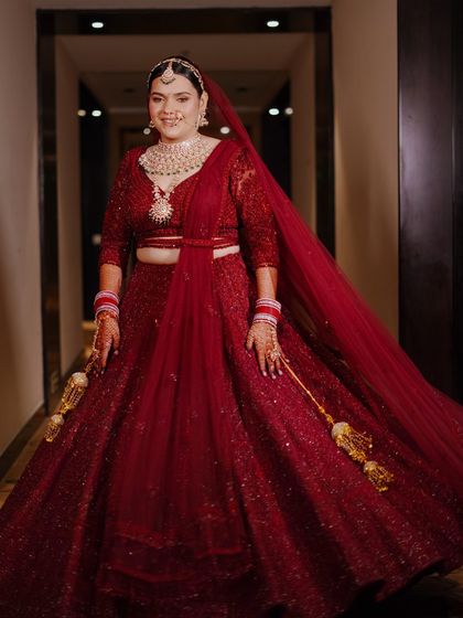 A full-length portrait of the bride, Muskan, twirling in her red lehenga. The movement and her radiant smile capture the joy of her wedding day.