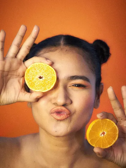A fun, playful wink and pout with orange slices. This kind of expressive modeling is perfect for creating relatable and shareable content for social media campaigns.