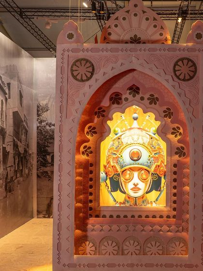 A detail from the 'Indofuturism' installation, where a backlit AI-generated portrait glows within an ornate, hand-crafted frame. This piece embodies the theme's blend of familiar landscapes and the intriguing allure of retro-futuristic narratives.