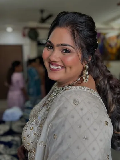 A beautiful over-the-shoulder shot. The client's makeup is soft and radiant, with a focus on glowing cheeks and a defined eye.