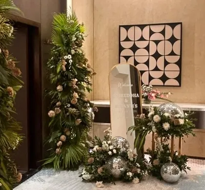 This image shows the entrance area for a cocktail party. We used tropical foliage arrangements and scattered disco balls around the welcome sign to create a chic and modern party vibe.