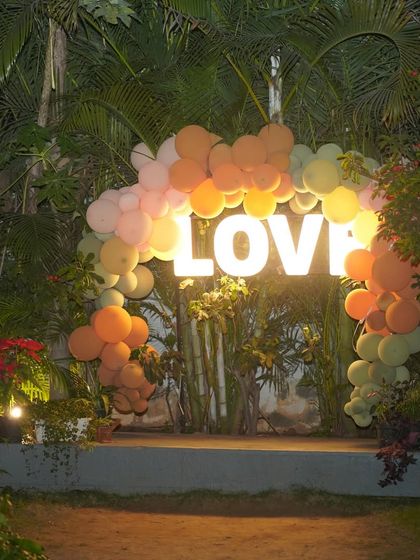 This "LOVE" marquee sign surrounded by a balloon arch creates a perfect photo booth for a birthday or anniversary celebration, especially for outdoor evening events.