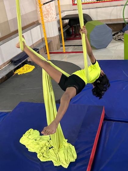 This young student demonstrates a side stretch pose on the silks, a great way to improve flexibility and balance.