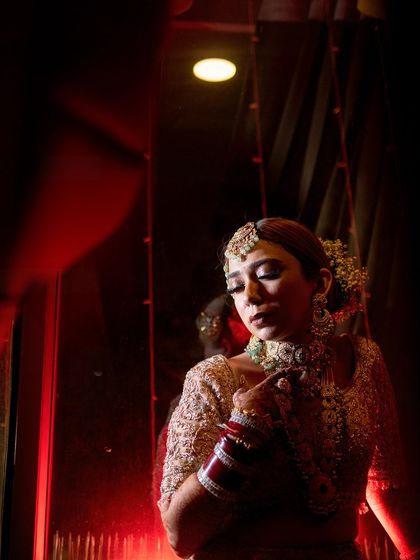 A reflection of the bride. This image uses reflections and dramatic red lighting to create a powerful and artistic wedding photo, showcasing the versatility of the makeup look.