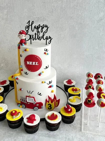 A fun and modern fireman-themed dessert table for Neel's 3rd birthday. The clean, simple cake is paired with cupcakes and cake pops decorated with firefighter hats and hydrants.