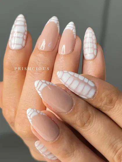 Croc nails on point! This trendy design features a textured, hand-painted crocodile print in white on a nude base, with some nails as a modern French tip.