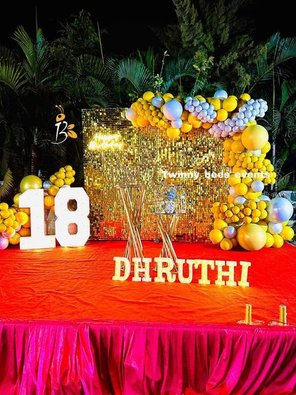 An 18th birthday celebration with a touch of glam. We used a gold shimmer wall as the backdrop, accented with a yellow and blue balloon garland and large marquee numbers.