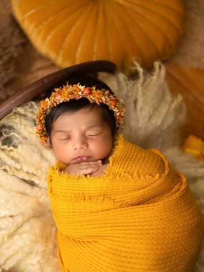This little bundle of sunshine is wrapped in yellow and resting in a prop, surrounded by bohemian-style decor. I love creating these warm, textured setups.