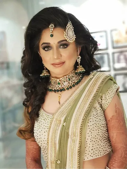 Your reception look should be just as stunning as your wedding day makeup. For this bride, we chose a glamorous smokey eye and a soft nude lip to match her elegant green saree. Her hair was styled in voluminous waves, creating a modern and chic look for her evening celebration.