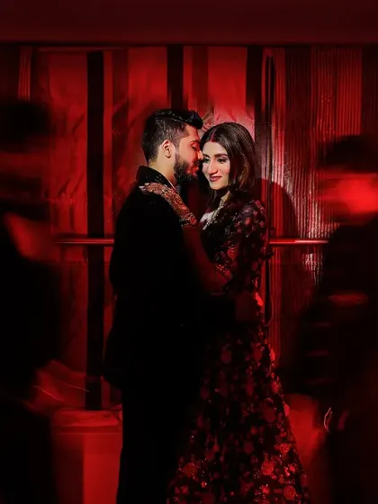 A passionate and moody indoor shot with a creative use of red light and motion blur. The effect suggests a hidden, intimate moment in a bustling, energetic space.