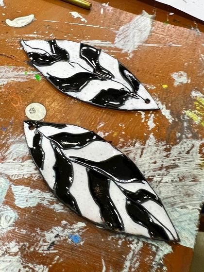A pair of finished enamel earrings on our messy, well-loved studio table. Each piece is a unique work of wearable art.
