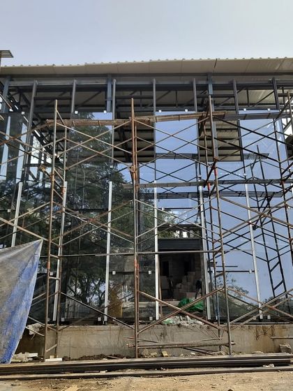 The glass facade of the Experience Center reflecting the sky, even while surrounded by scaffolding.