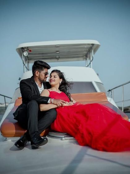 A glamorous pre-wedding photo on a yacht. The couple looks relaxed and happy, with the red gown adding a touch of luxury.