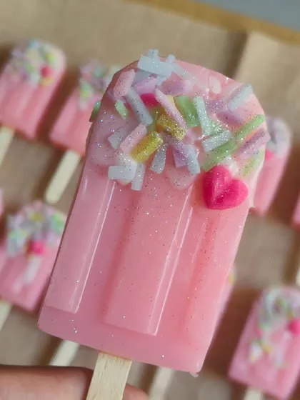 Holding up a sprinkle-topped popsicle soap to show its size and sparkly details.