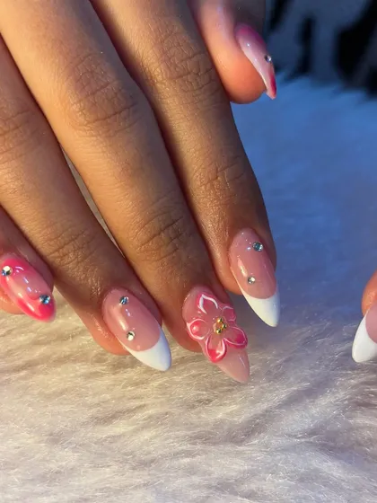 These nails scream vacation. We created this fun look with a pink ombré base, classic white French tips, and adorable 3D pink flowers, all accented with tiny rhinestones.