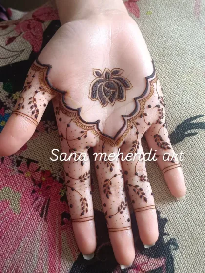 A unique design on the palm featuring a lotus and rose motif. The pattern extends down the fingers with delicate leafy vines, creating a very pretty and modern look.