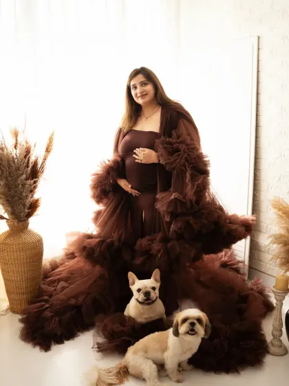 A portrait for the whole family, including the fur babies. The mother-to-be stands proudly in a beautiful gown, surrounded by her adorable dogs.