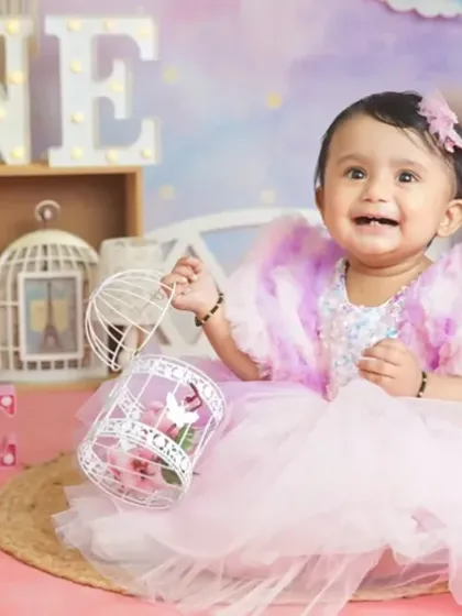 A little princess in her pink and purple tulle dress, looking adorable during her first birthday photoshoot.