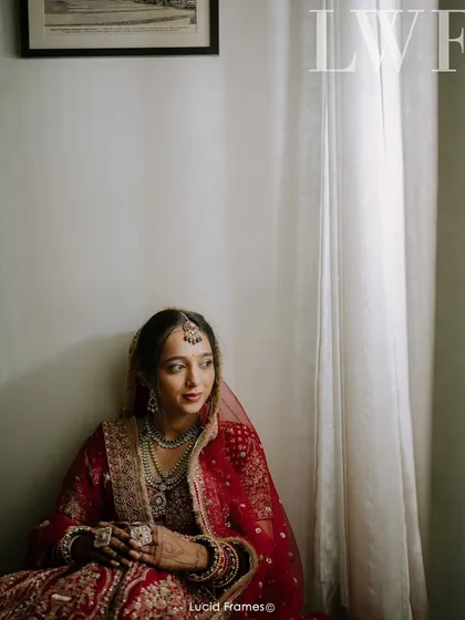 A quiet, contemplative portrait of the bride sitting by a window, bathed in soft, natural light.