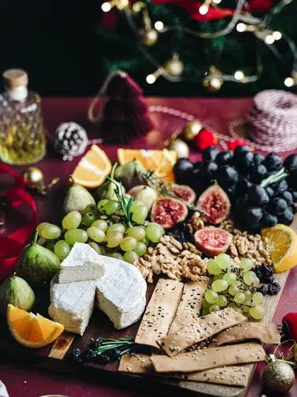 Happy Christmas Eve. A beautiful, abundant cheeseboard styled with fresh fruits, nuts, and crackers against a backdrop of a Christmas tree. It's a perfect picture of holiday indulgence.