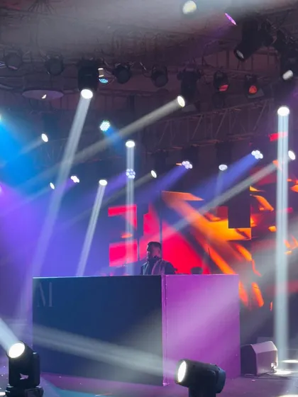 A shot from a distance, showing how the DJ console becomes the focal point of the stage. The lighting and stage design are key to building a party atmosphere.