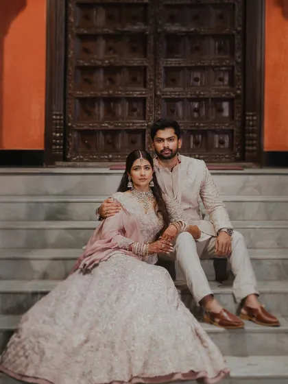 A stunning editorial-style portrait of the couple seated on steps. The grand setting and their elegant poses give this image a royal and cinematic quality.