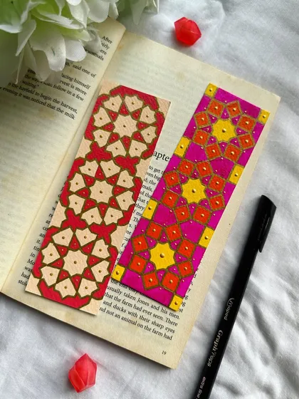 These bookmarks are inspired by Islamic geometric patterns. The one on the right features a bright pink and orange design, while the one on the left uses a more subdued red and cream palette.