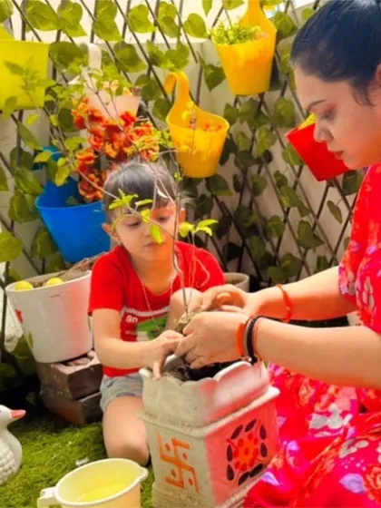 A mother and daughter work together to plant a sapling in their balcony garden, participating in our school's green initiative.