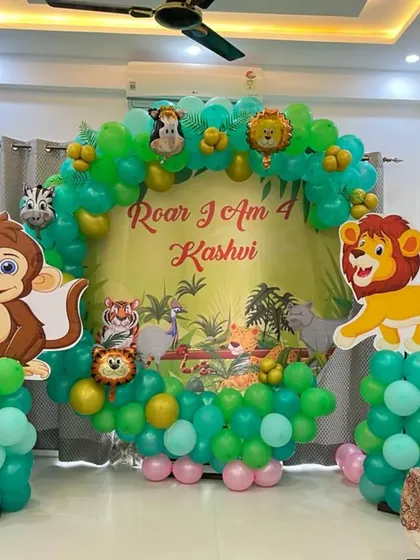 For kids' birthdays, I create fun, themed decorations like this jungle-inspired setup for a 4th birthday. It includes a full balloon arch in shades of green, a personalized backdrop, and large cutouts of favorite animal characters like a monkey and lion, making it a great photo spot.