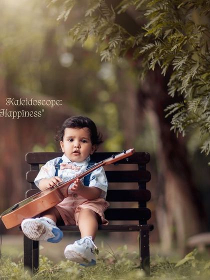 A kiddie kaleidoscope of joy and happiness. A toddler sits on a park bench, holding his ukulele and looking contemplative.