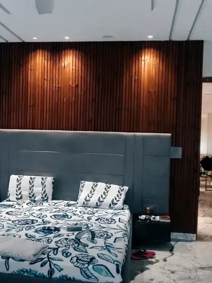 A finished bedroom with a floor-to-ceiling wood-paneled accent wall. The spotlights are strategically placed to highlight the texture of the wood, creating a warm and inviting focal point in the room.