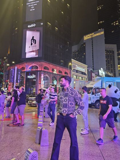 Our client looking amazing in our creation while exploring the vibrant city streets at night. His printed shirt and flared jeans make a stylish statement.