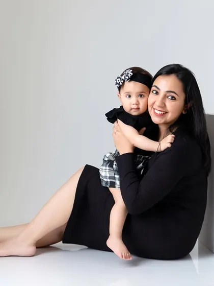 A mother and daughter smile for the camera in a classic seated pose. The minimal props and background ensure the portrait is timeless and focused on them.