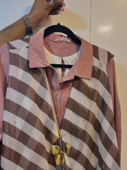A behind-the-scenes glimpse of the wardrobe for the Amazon Alexa shoot. This shows the actual pieces, a striped vest over a pink shirt, before they came to life on set.
