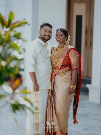 A classic portrait of the bride and groom in their traditional South Indian wedding attire, standing together as they begin their new life.