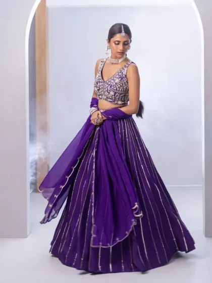 This vibrant purple lehenga is for the bride who loves colour. The heavily embellished blouse, paired with a flowing skirt with metallic stripes, is ideal for a sangeet or mehendi celebration.