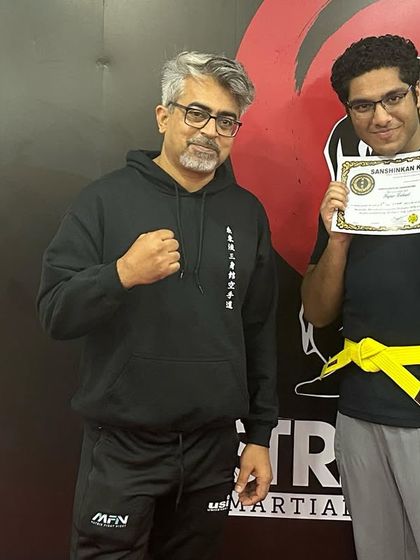 A student receives his yellow belt in kickboxing from a senior sensei, marking his progress and dedication.