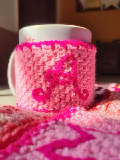 A custom mug cozy order that was sent to Mumbai. This one, with the initial 'A', is in a vibrant pink. It keeps your hands safe and your drink warm.