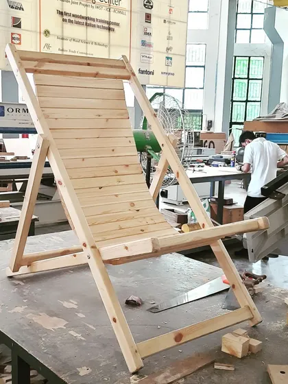 Another view of the student-made lounge chair, showing its profile against the backdrop of the busy workshop where it was created.