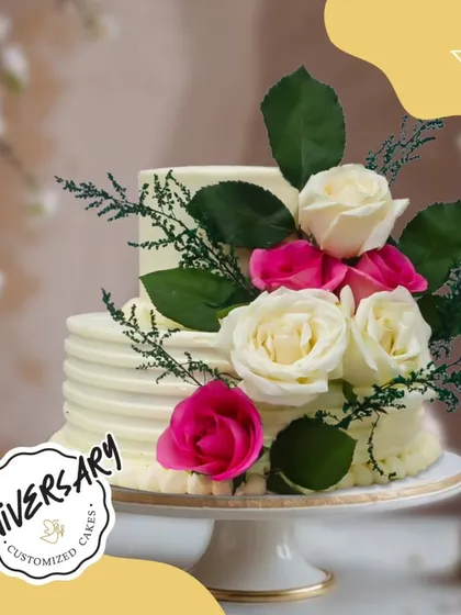 A classic two-tier anniversary cake, adorned with fresh white and pink roses. The simple elegance of this design makes it a timeless choice for celebrating love.