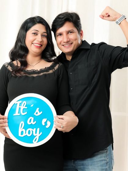 It's a boy! This couple's excitement is contagious as they hold up a sign to announce their baby's gender during their studio session.