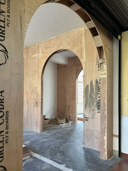 This is the very beginning of the entrance experience. The raw plywood structure shows the creation of the nested arches that would eventually become the dramatic, fabric-wrapped doorway and entryway, setting the stage for the entire boutique.