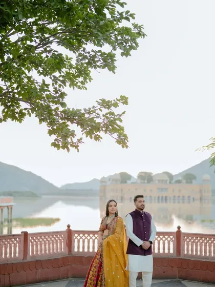 We use iconic Jaipur landmarks like Jal Mahal to create breathtaking backdrops. This photo shows a couple standing against the serene lake and palace, demonstrating how we incorporate famous scenery into your love story.