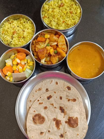 A look at one of our daily lunch tiffins, packed with lemon rice, aloo gobi sabzi, simple dal, two rotis, and a fresh salad. It's a perfect midday meal to keep you energized.