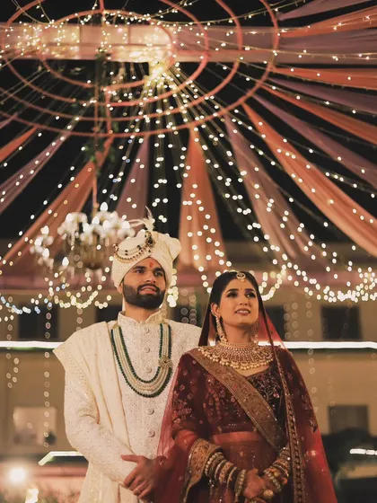 A stunning wide shot of the couple under a canopy of fairy lights. This kind of grand, atmospheric portrait is perfect for capturing the scale of the celebration.