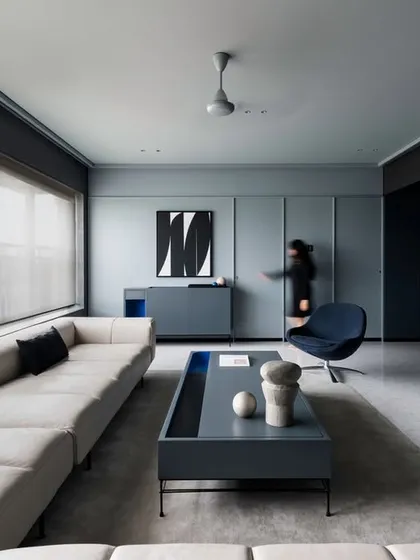 This living room from our 'A Hint of Azul' project demonstrates how partitions can define space without enclosing it. A curved, slatted partition separates the living and dining areas, allowing natural light to filter through while seamlessly integrating the HVAC system. The cool grey palette is punctuated by strategic hints of blue, creating a calm yet dynamic environment.