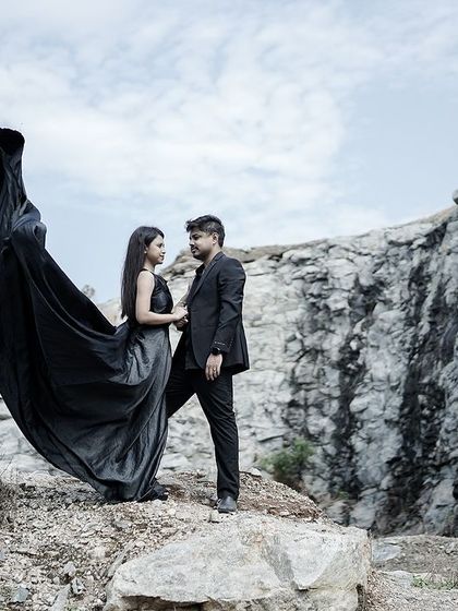 An intimate yet powerful pose amidst a rocky landscape, with the bride's black gown creating a striking silhouette.