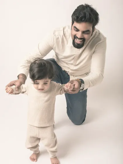 Guiding his first steps. A father's pride and joy are evident as he helps his son learn to walk.