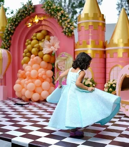 Another photo of the birthday girl twirling, this time showing off the checkered dance floor and the royal carriage prop at her Disney-themed party.