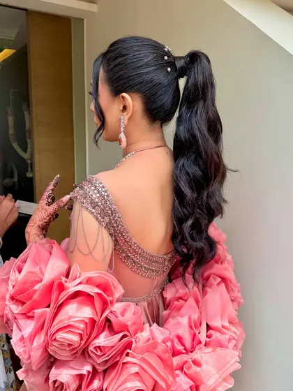 A glamorous high ponytail with soft, voluminous waves, accented with delicate pearls at the base. This chic and modern hairstyle is a fantastic choice for a Sangeet or Cocktail party, offering both style and comfort for a night of dancing.